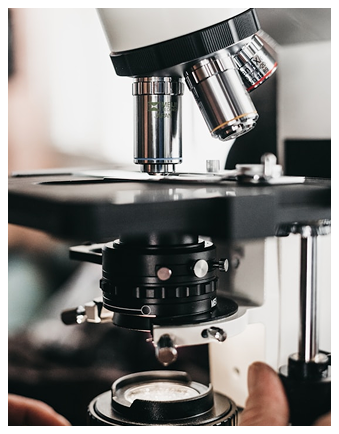 Close-up of a laboratory microscope's objective lenses and stage with a slide in place.